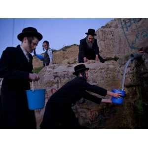 Ultra Orthodox Jewish Men Stand Next to a Well as They Fill Canisters 